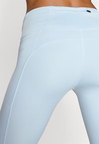 Világoskék sport leggings, sima textúrával, magas derékkal és varrás részletekkel, a kényelem és rugalmasság érdekében tervezve.
