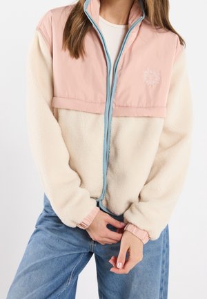 Fleecejack met een crèmekleurig ondergedeelte en een roze bovenstuk, heeft een blauwe rits en geribde roze manchetten, geborduurd zonlogo op de borst.