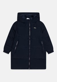 Marineblå polstret jakke med hette, med glidelås foran, to sidelommer og en liten logo. Myk tekstur og quiltet design.