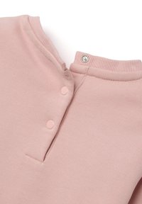 Top en coton rose clair avec un col rond, doté de deux boutons pression et d'une fermeture à pression en métal. Tissu doux et texturé.