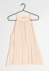 Top senza maniche di un delicato colore pesca chiaro con scollatura tonda, tessuto arricciato e aperture laterali. Realizzato in materiale morbido e leggero. Appeso a un gancio nero.