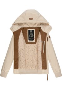 Veste à capuche beige avec doublure intérieure marron, tissu intérieur à motifs et étiquette portant l'inscription "Soyez le changement" à l'intérieur du col.