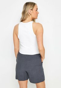 Witte geribbelde tanktop gecombineerd met donkergrijze linnen shorts, met zakken en een relaxte pasvorm. De achterkant toont een eenvoudig ontwerp.