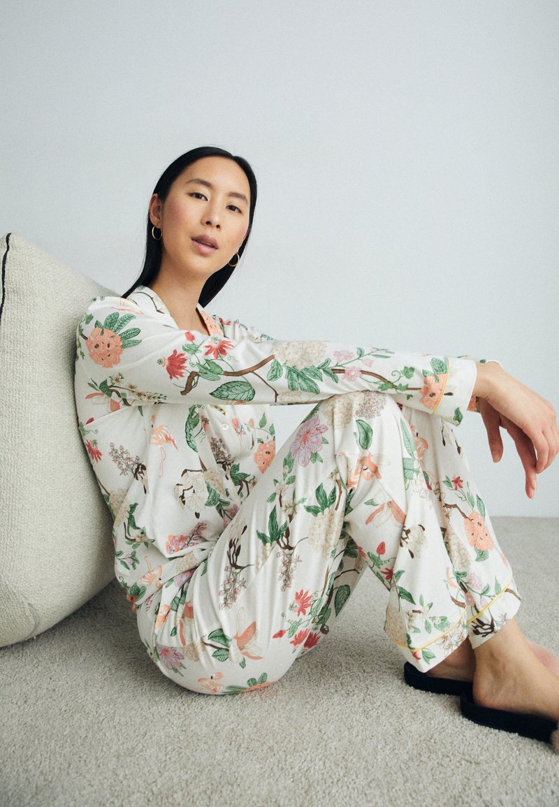 Floral-patterned loungewear set in light fabric, featuring long sleeves and pants, with shades of pink, green, and cream. Cozy texture.