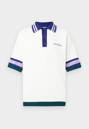 Balta polo krekls ar teksturētu adījumu. Tam ir tumši zilas krāsas apkakle ar svītrām un svītraini violetas un zaļas krāsas akcenti uz piedurknēm. Izšūts zīmols.