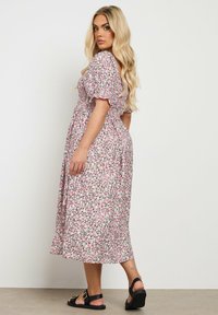 Midikjole med blomsterprint i pink og grøn, puffærmer, smocked bodice og en let flowy bund. Båret med sorte sandaler.