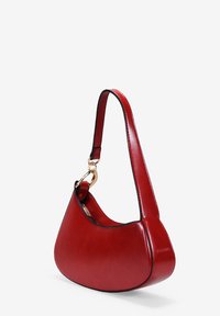 Bolso de hombro de cuero rojo con una silueta curva, que presenta una textura suave, una correa corta y detalles en hardware dorado.