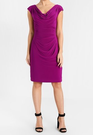 Robe drapée violette avec des manches courtes, présentant un col bénitier et une silhouette ajustée, associée à des talons noirs à lanières. Texture lisse.