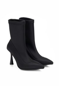 Bottes cheville noires en matière extensible, avec un bout pointu et des talons hauts fins. Présentent un design épuré et sans couture, ainsi qu'une surface texturée.