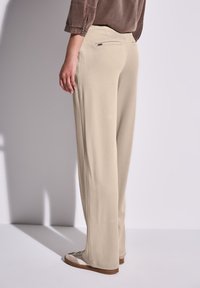 Pantaloni beige, dal taglio morbido e dritto. Presentano una tasca posteriore discreta e un design pulito e minimal.