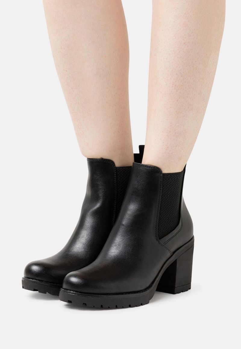 Schwarze Leder-Stiefeletten mit einem dicken Absatz und elastischen Seitenpaneelen. Glatte Textur mit einer abgerundeten Spitze und profiliertem Sohlen für besseren Halt.