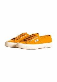 Sneakers di tela arancioni con suole in gomma bianca e lacci, caratterizzati da dettagli di cucitura e un piccolo etichetta con logo sul lato.