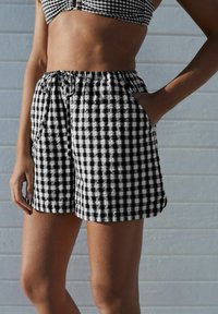 Schwarz-weiße karierte Shorts aus leichtem Stoff, mit elastischem Bund, Kordelzug und seitlichen Taschen.
