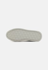 Sole di sneaker grigia chiara con design piatto e gomma testurizzata. Presenta indentazioni a motivo e un leggero marchio impresso in tutto il suo perimetro.