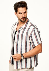 Kurzärmliges Hemd mit Knopfleiste, das einen weißen Grund mit roten und blauen vertikalen Streifen zeigt, einen Kragen hat und aus strukturiertem Stoff gefertigt ist.