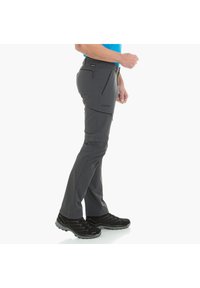 Pantalones exteriores grises de material ligero, con un diseño de pierna recta y bolsillos laterales con cremallera. Combinados con zapatos de trekking negros.