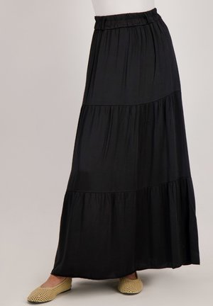 Zwarte, gelaagde maxi rok met een elastische tailleband, gemaakt van lichte materialen. Heeft een soepele textuur en valt tot op de enkel.