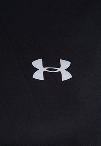 Tela negra con una textura suave que presenta un destacado logo blanco de Under Armour en el centro, exhibiendo un diseño minimalista.