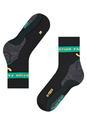 Calze nere con accenti verdi e gialli. Zone del tallone e della punta rinforzate, con un design testurizzato in nero e grigio. Nome del marchio visibile.