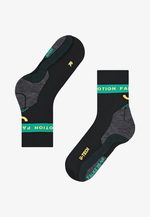 Schwarze Socken mit grünen und gelben Akzenten. Verstärkte Fersen- und Zehenbereiche mit einem strukturierten Design in Schwarz und Grau. Markenname angezeigt.