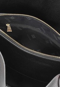 Interno di una borsa a tracolla in pelle nera con una cerniera dorata, dotata di una tasca e un rivestimento in tessuto decorato con un design di logo.