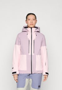 Fargeblokkerte jakke med lyserosa og lavendelpaneler, hette, glidelåsede frontlommer og svarte detaljer. Laget av slitesterkt stoff.