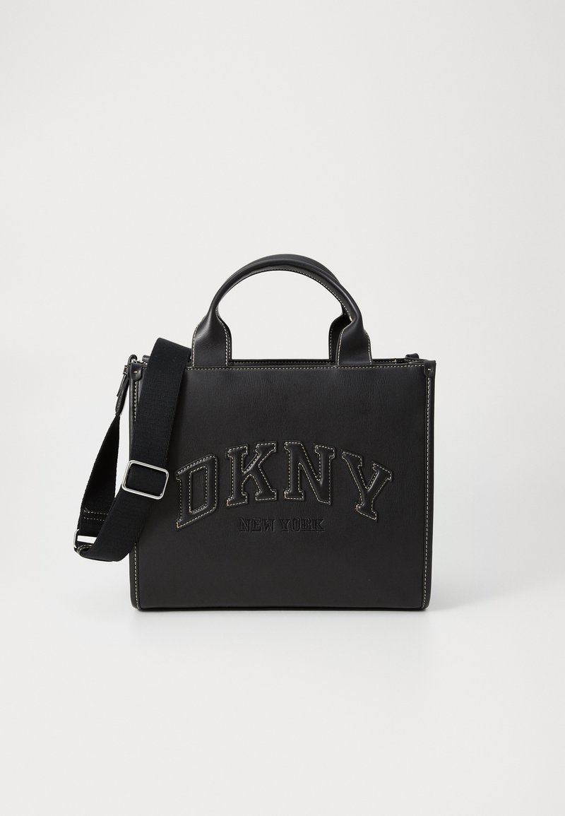 Zwarte leren handtas met dubbele handvatten, verstelbare schouderriem, geperst "DKNY" logo en witte contrasterende stiksels. Gestructureerde rechthoekige vorm.