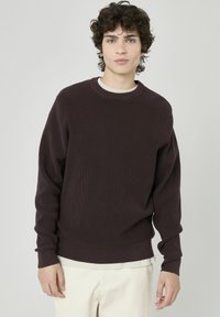 Sweatshirt côtelé de couleur brun foncé avec manches longues et col rond, présentant une texture douce et un subtil bord intérieur contrasté.
