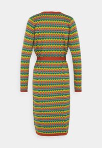 Šaty s dlouhým rukávem s živým, vícebarevným zigzag vzorem. Vyrobeno z texturovaného pleteného materi álu, s přiléhavým pasem a červenými akcenty.