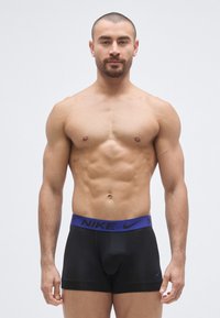 Sorte Nike boxer briefs med en bred lilla linning med Nike-logoen. Glat materiale, tætsiddende design og uden mønstre eller detaljer.