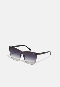Ochelari de soare negri cu un cadru unghiular, lentile cu un gradient de la întunecat la deschis și brațe cu marcă, prezentând litere albe. Concepuți pentru estetica modernă.