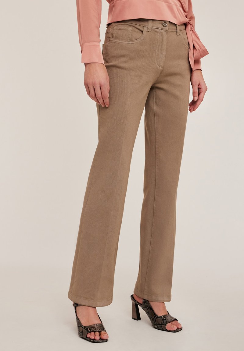 Beige rechttoe-rechtaan broek met een textuurafwerking, vijf zakken en een knoopsluiting, gecombineerd met zwarte open hakken.