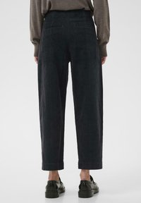 Donkergrijze corduroy broek met een hoge taille, rechte pijpen en opgerolde mouwen. Heeft twee achterzakken en een zachte textuur.