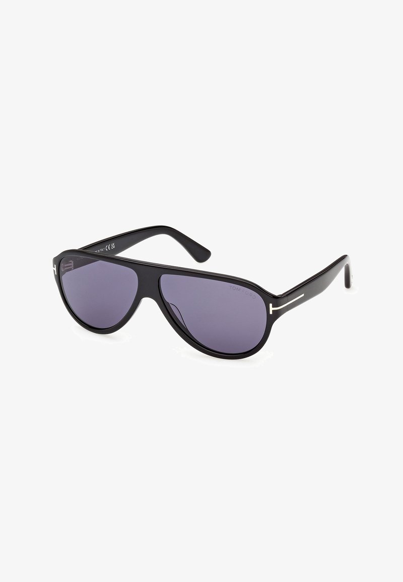 Lunettes de soleil aviator noires avec des verres foncés et des branches fines ornées d'un logo argenté en forme de T discret près des charnières.
