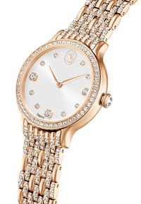 Zegarek w kolorze różowego złota z teksturowanym paskiem i kryształowymi akcentami. Biała tarcza z złotymi wskazówkami i dwunastoma diamentowymi znacznikami, otoczona kryształami.