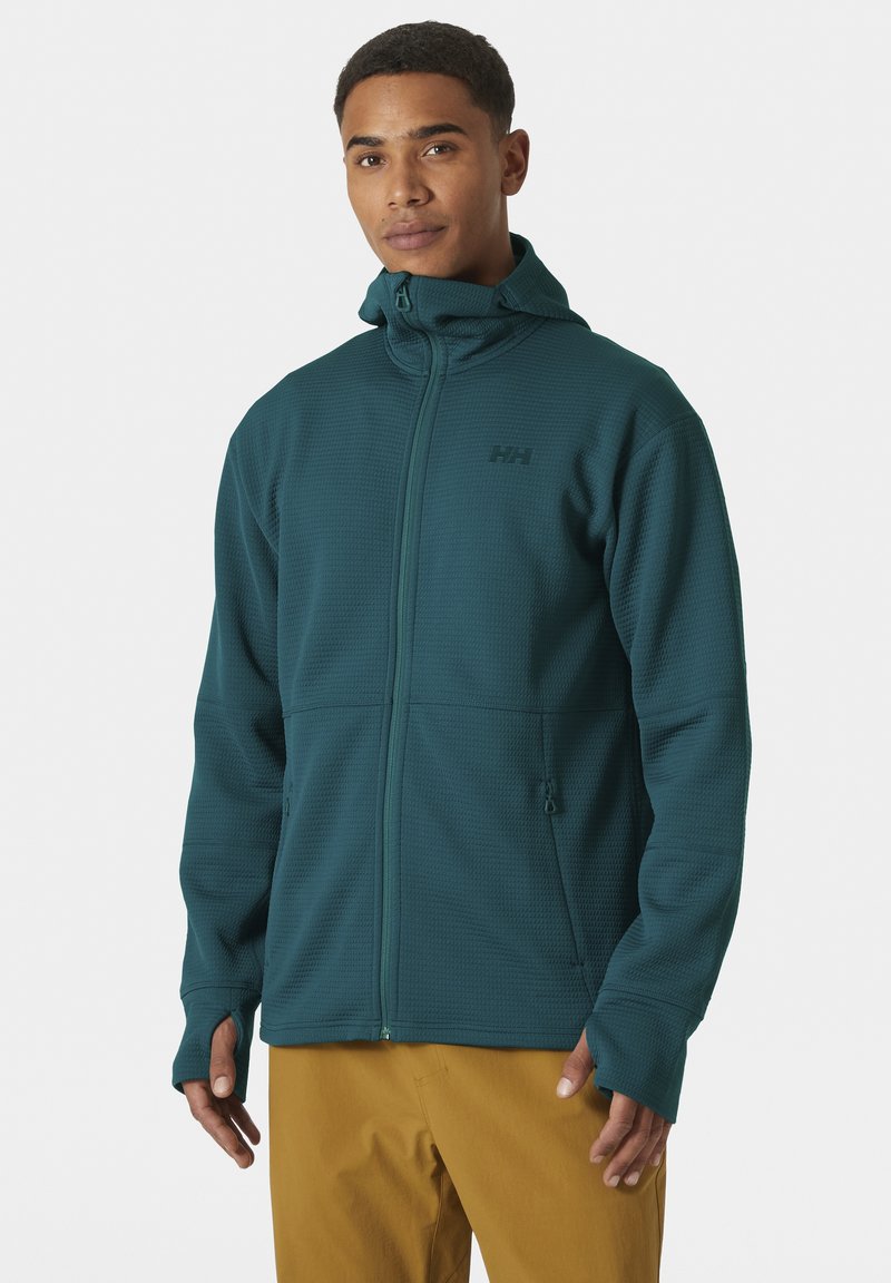 Chaqueta de forro polar texturizado en tono verde azulado con cremallera completa, cuello alto y agujeros para los pulgares. Cuenta con dos bolsillos con cremallera y un logo sutil en el pecho.