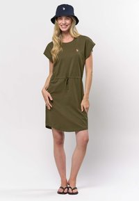 Olivovo zelené šaty s voľným strihom, krátkymi rukávmi, nastaviteľným šnúrkovým pásom a bočnými vreckami. Kombinované s tmavomodrým klobúkom typu bucket.