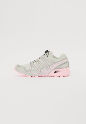 Világosszürke sportcipő rózsaszín kiegészítőkkel, textúrált felsőrésszel, légáteresztő hálóval és különleges mintázatú gumitalppal.