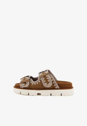 Infradito in suede marrone con dettagli intrecciati beige, due cinturini regolabili, una soletta testurizzata e una suola spessa bianca.