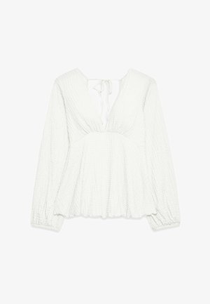Haut blanc texturé avec un deep V-neck et une fermeture à nouer à l'arrière. Présente des manches longues avec des poignets élastiques et une coupe fluide et décontractée.