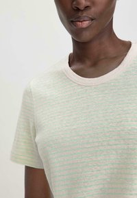 Lichtbeige t-shirt met mintgroene strepen, een ronde halslijn en korte mouwen. Zachte stofstructuur met een casual pasvorm.
