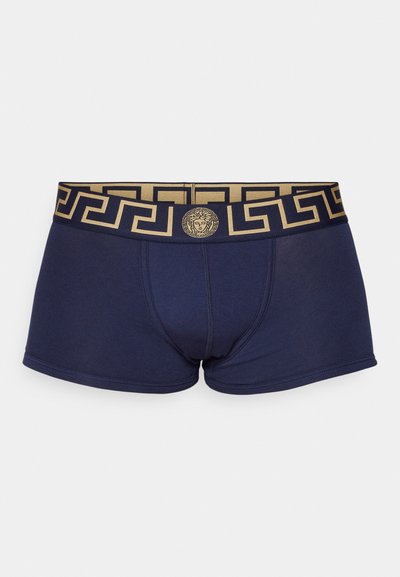 Mornarsko modri boksarji z zlato grško ključno obliko na pasu, ki imajo osrednji izboklinski logotip. Narejeni so iz mehke, elastične tkanine.