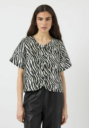 Svart och vit zebra-randig kortärmad blus med rundad halsringning och knappar framtill, tillverkad i ett slätt tyg.