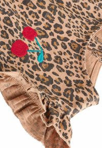 Leopardenmuster-Stoff mit einem hellbraunen Grund, der rote gestickte Kirschen mit einem türkisfarbenen Stiel und einem gerafften Saumdetail zeigt.