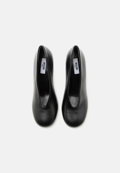 Ζευγάρι μαύρα δερμάτινα μπαλαρίνες με στρογγυλεμένες μύτες και ετικέτες Moschino Milano στο εσωτερικό, φωτογραφημένα από πάνω σε λευκό φόντο.