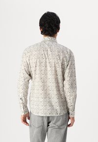 Lange mouwen shirt van lichtgewicht stof, bedekt met kleine geometrische vormen in gedempte kleuren. Bevat een klassieke kraag en knoopmanchetten.