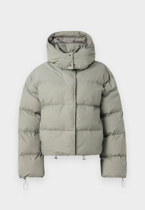 Jachetă tip puffer în verde estompat, cu guler înalt, croială supradimensionată, textură matlasată și șnururi ajustabile la tiv și la manșete.