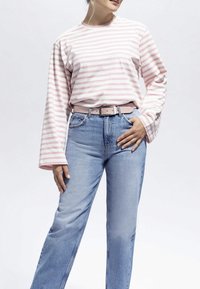 Camisa de algodón a rayas en rosa y blanco de manga larga combinada con jeans de mezclilla azul claro y un cinturón rosa a juego. Ajuste casual y estilo relajado.
