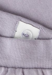 Jasnofioletowa dzianina o prążkowanej fakturze, z białą metką i przezroczystym plastikowym guzikiem.