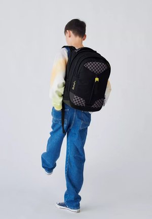 Zaino nero con dettagli a scacchi, cerniere e un particolare in metallo giallo. Il design è strutturato con spallacci imbottiti per garantire comfort.
